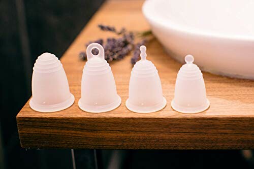 Vier menstruatiecups op houten oppervlak.