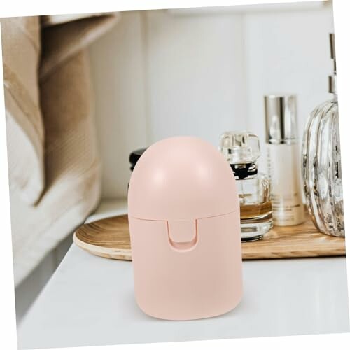 Roze zeepdispenser op een witte toonbank met achtergrond van toiletartikelen.