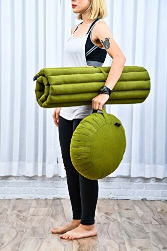 Persoon met groene yogamat en meditatiekussen